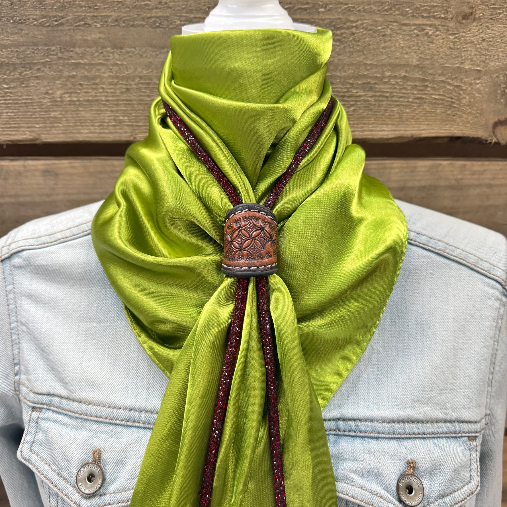 a green scarf tied to a jacket on a mannequin