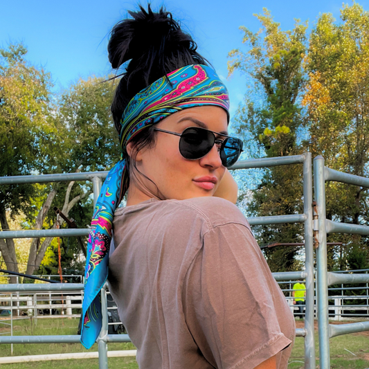 Person wearing sunglasses and a colorful wild rag headband with a scenic background