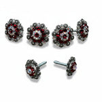 a collection of ornate, metallic jewelry pieces adorned with red gemstones. The jewelry includes earrings, necklaces, and bracelets, all showcasing intricate designs and sparkling gemstones.