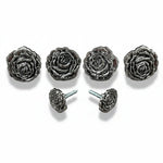 a collection of five ornate metal rose-shaped knobs or handles, each with a unique design and size.