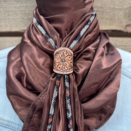 a woman wearing a brown scarf with a flower design on it
