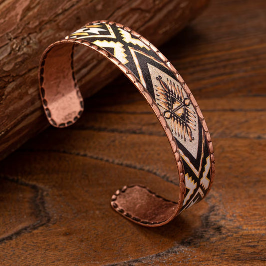Copper bracelet with tribal patterns on a wooden surface