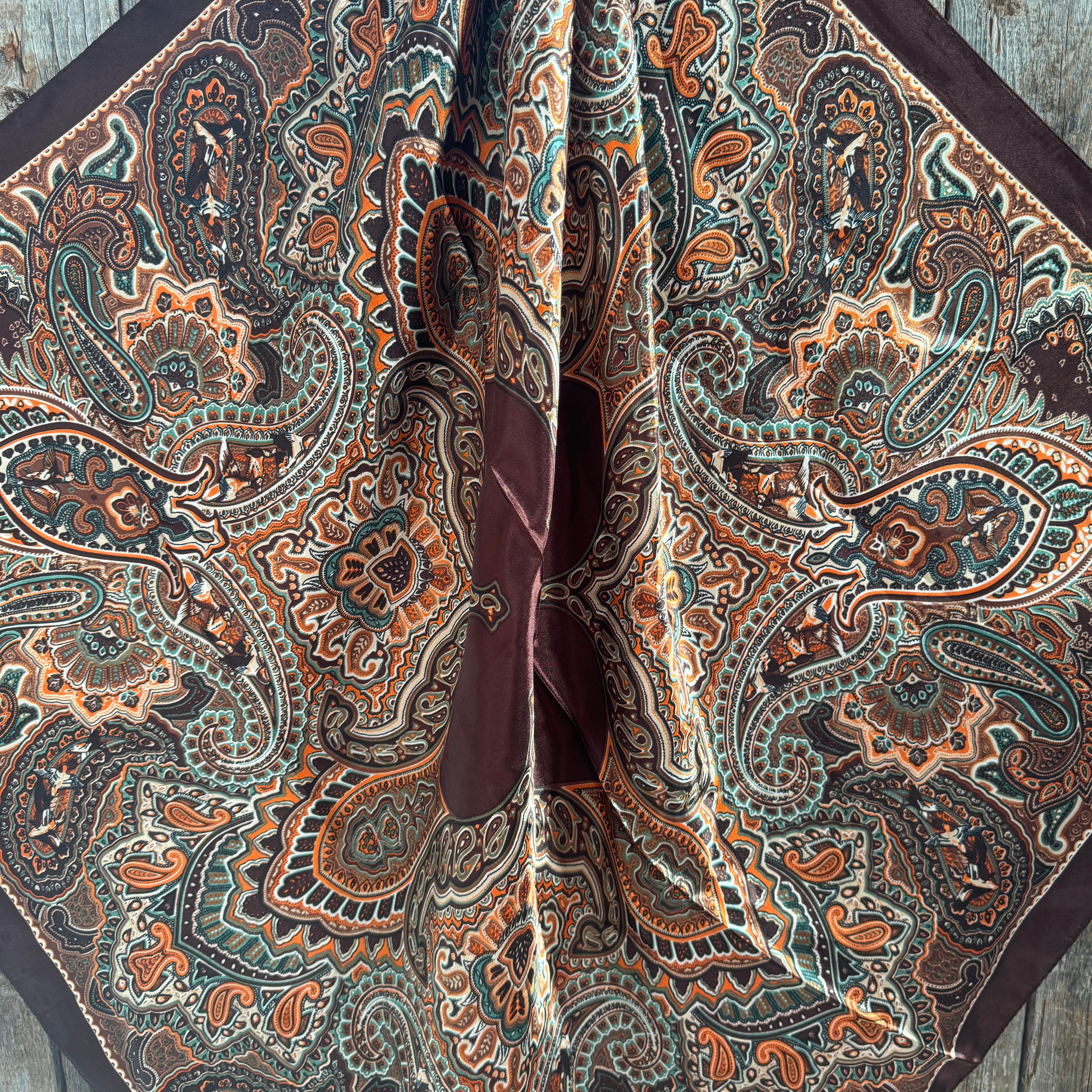 Close-up of a patterned wild rag scarf with intricate designs on a wooden surface