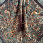 Close-up of a patterned wild rag scarf with intricate designs on a wooden surface