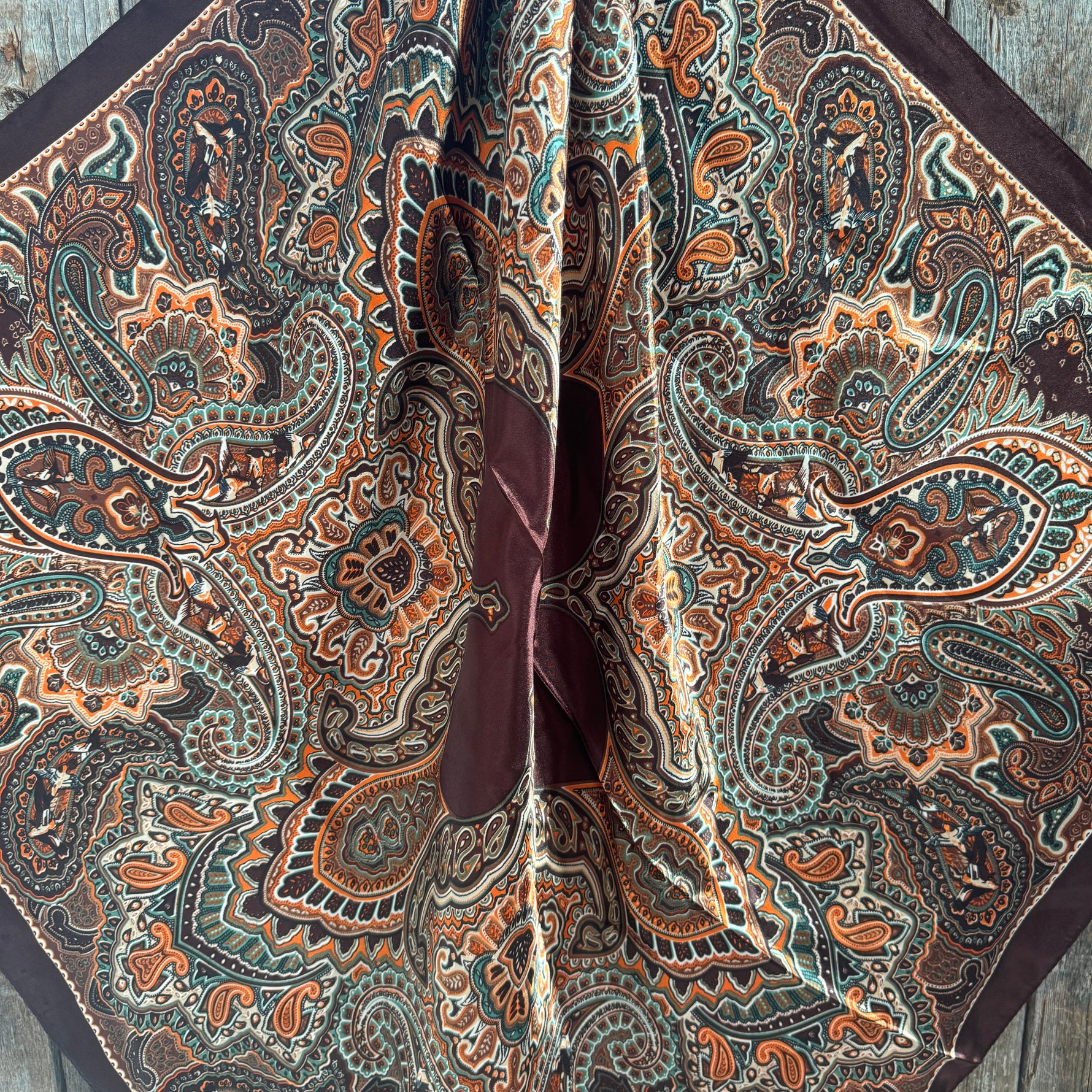 Close-up of a patterned wild rag scarf with intricate designs on a wooden surface
