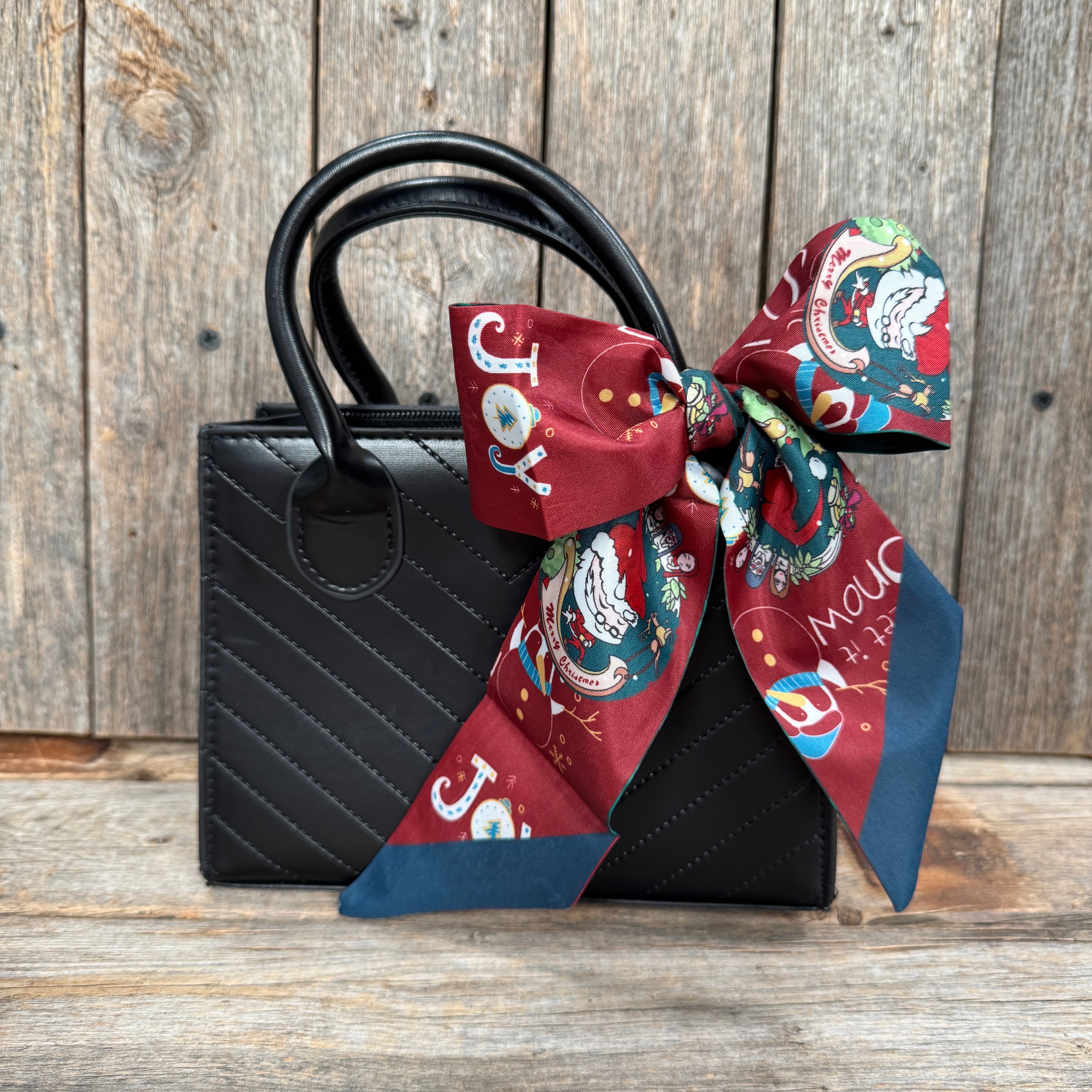 Black handbag with a decorative bow on a wooden surface