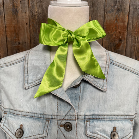 Light blue denim jacket with a large green bow on a wooden background