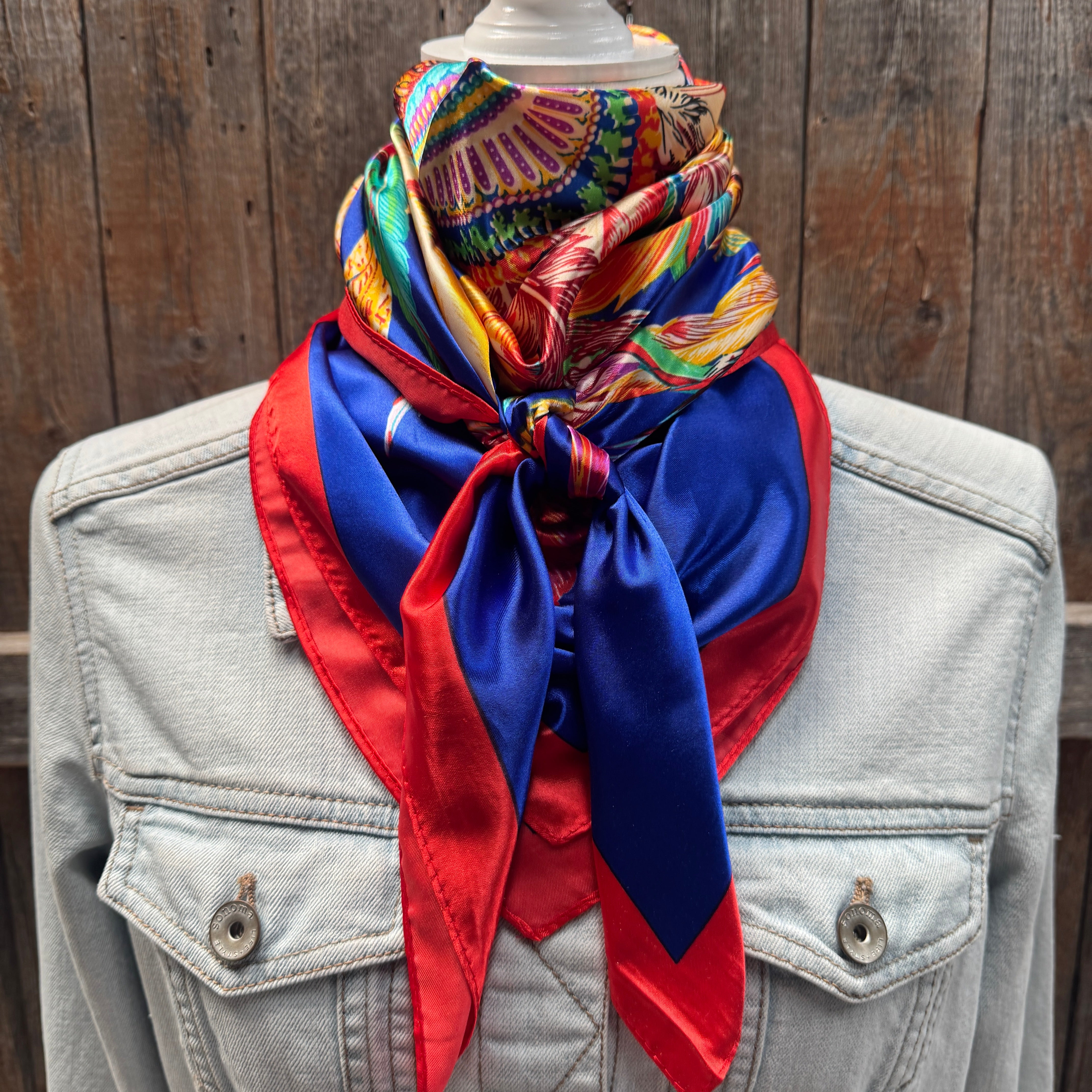 Colorful scarf draped over a denim jacket against a wooden background
