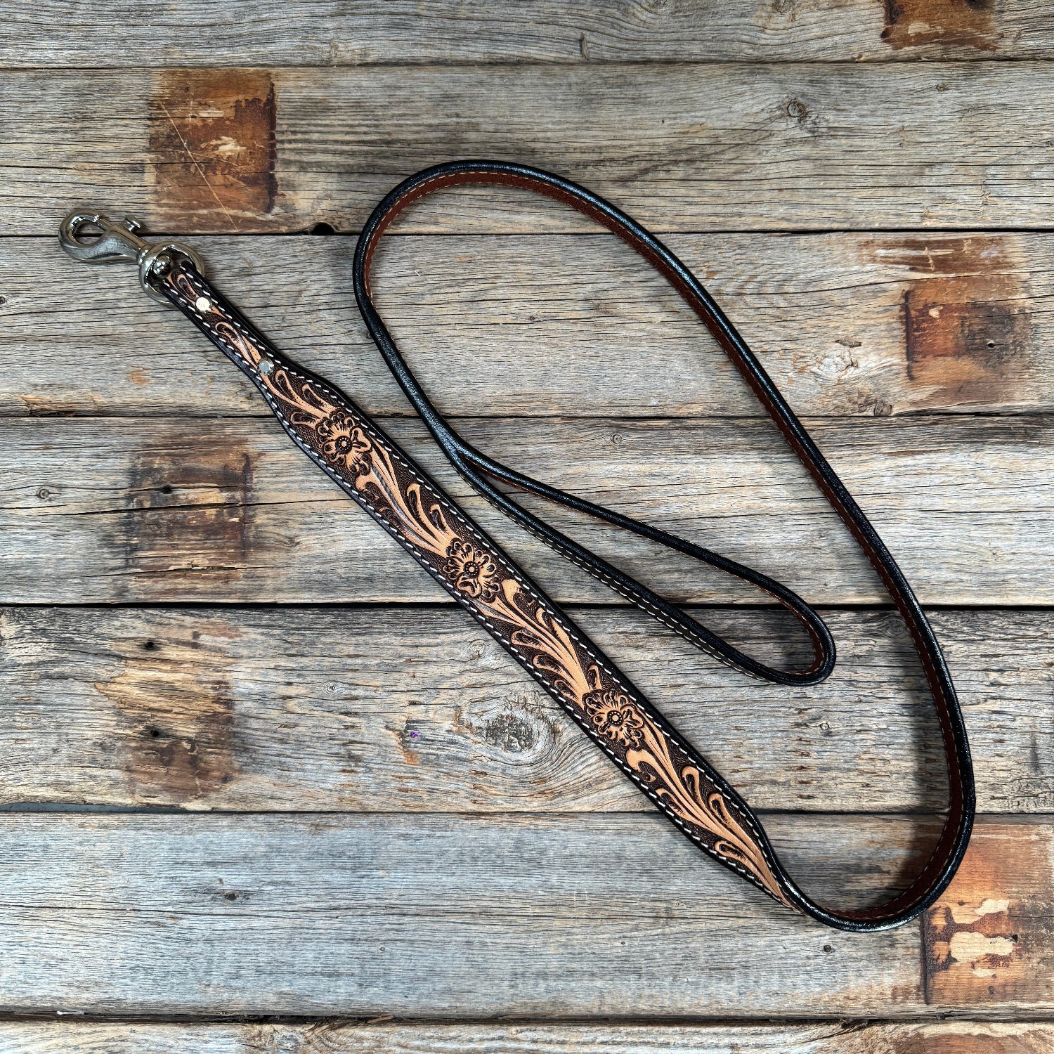 Decorative leather dog leash with intricate patterns on a wooden surface