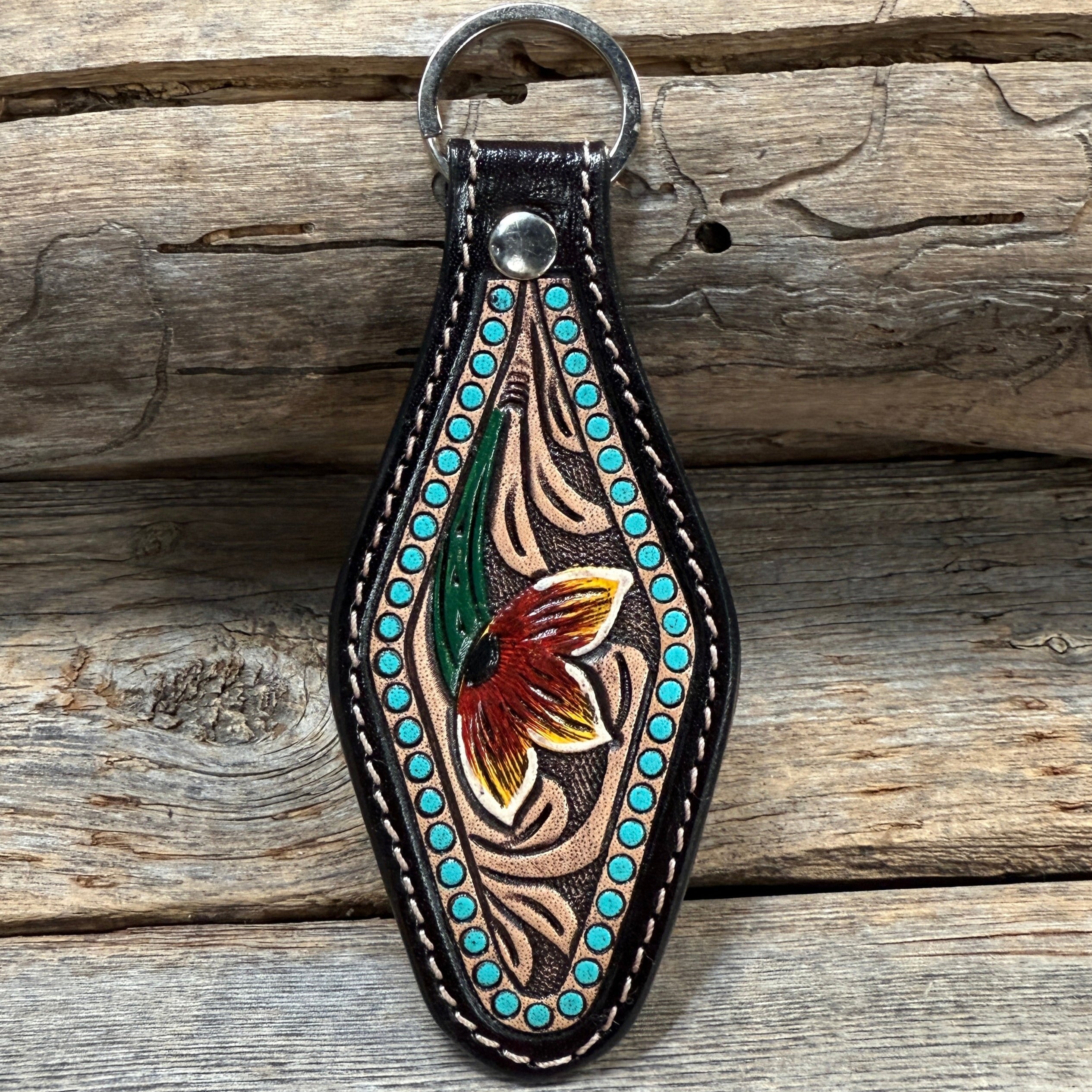 Decorative leather keychain with floral design on a wooden surface