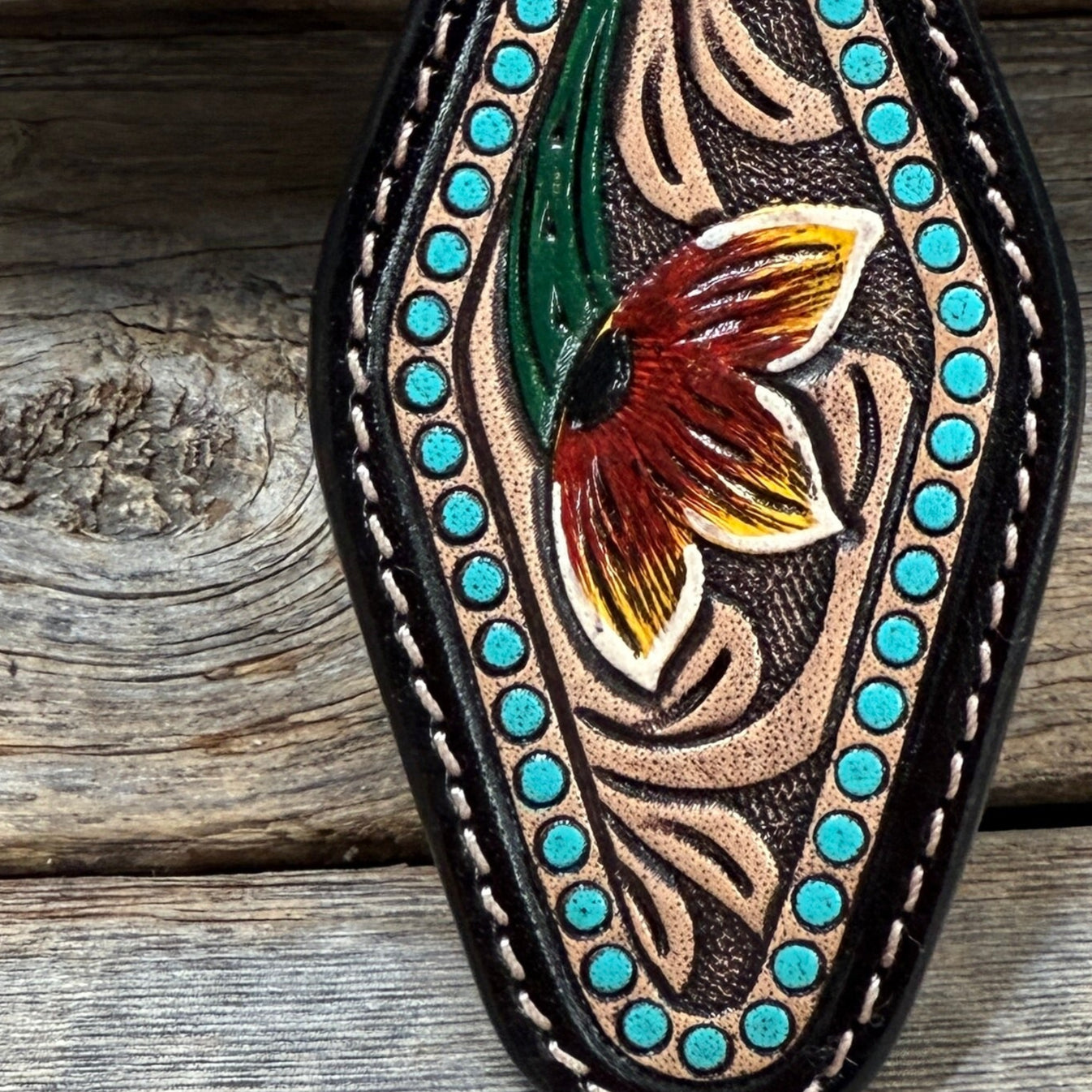 Decorative leather keychain with floral design on a wooden surface