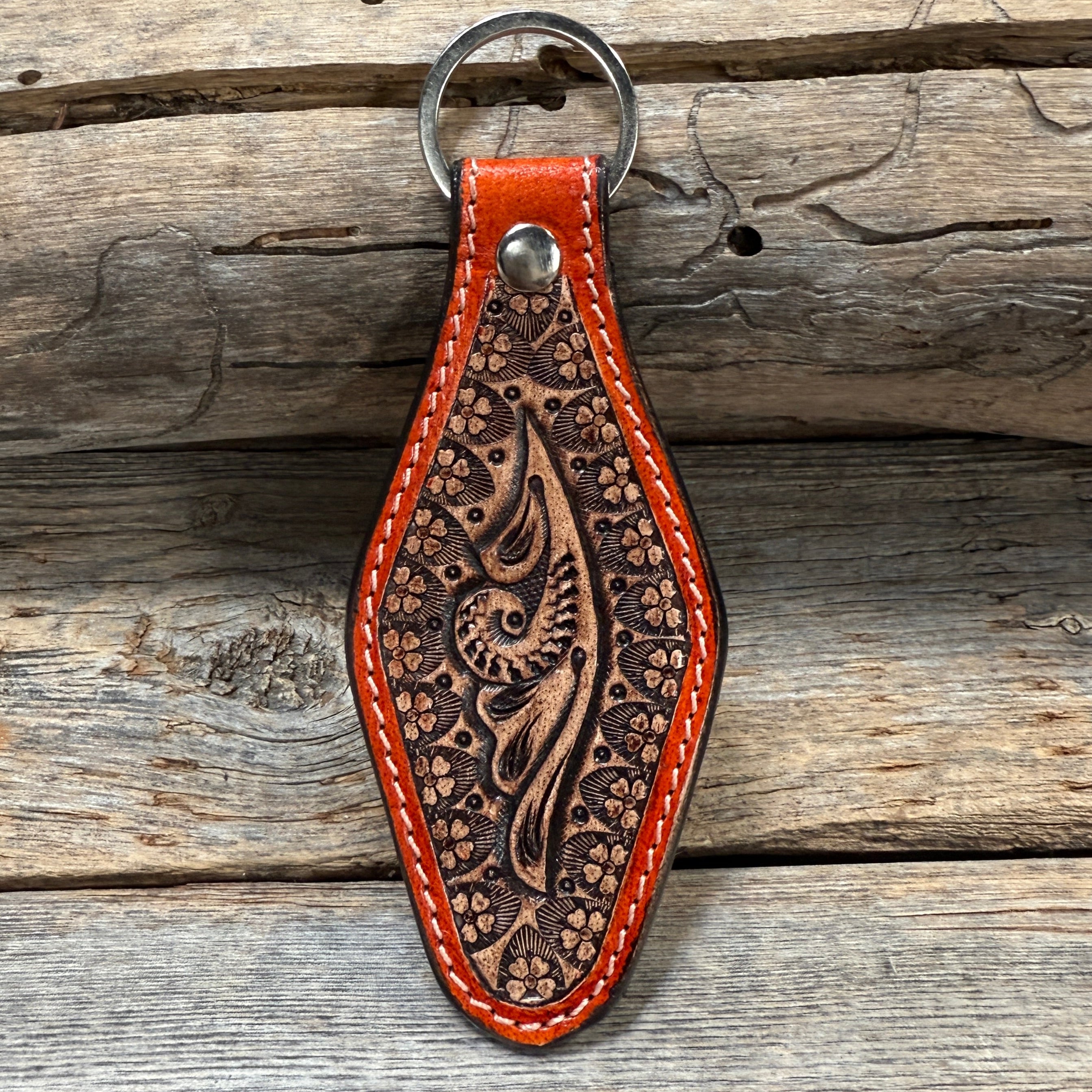 Brown leather keychain with intricate patterns on a wooden surface