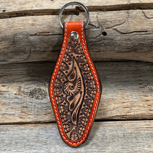 Brown leather keychain with intricate patterns on a wooden surface