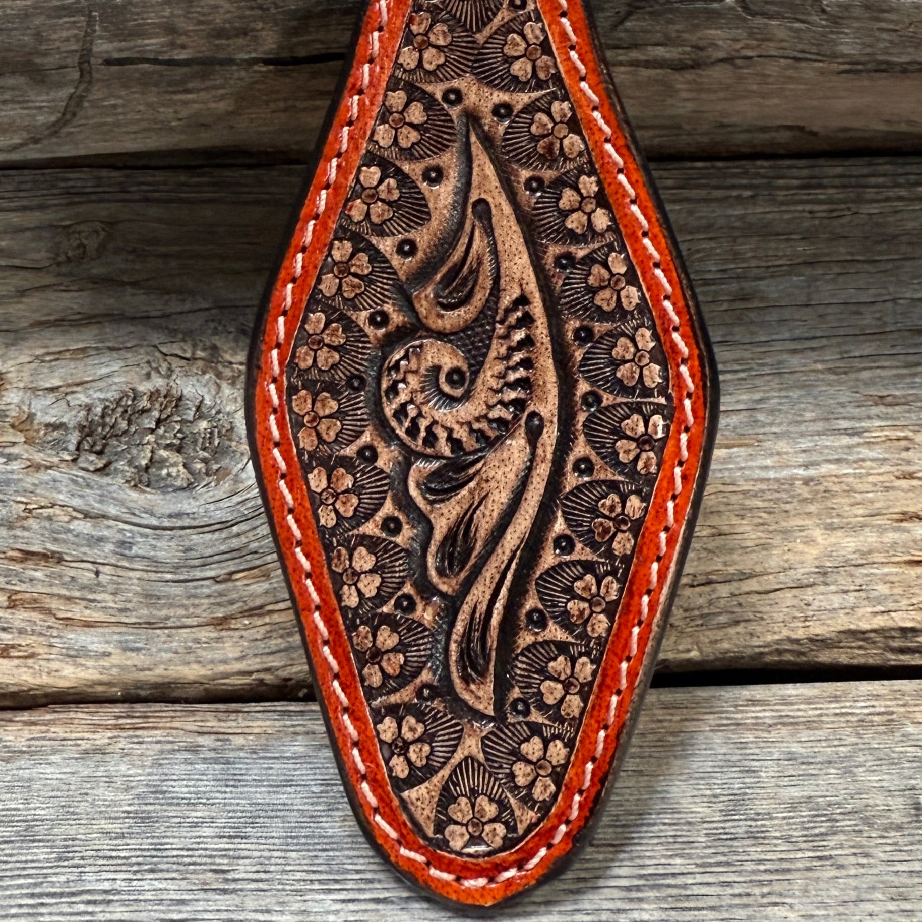 Brown leather keychain with intricate patterns on a wooden surface
