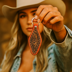 Person wearing a cowboy hat and holding a decorative leather keychain.