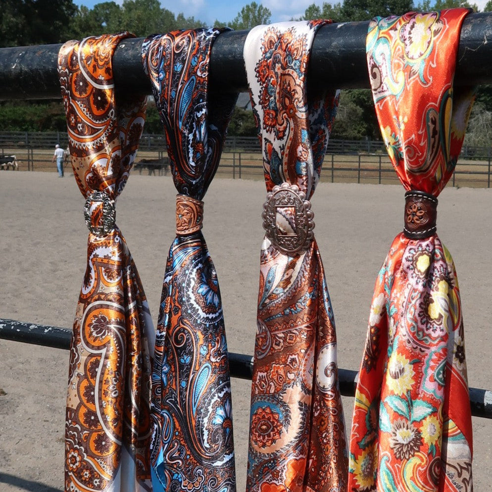Colorful patterned scarves tied to a railing with a background of an outdoor setting.