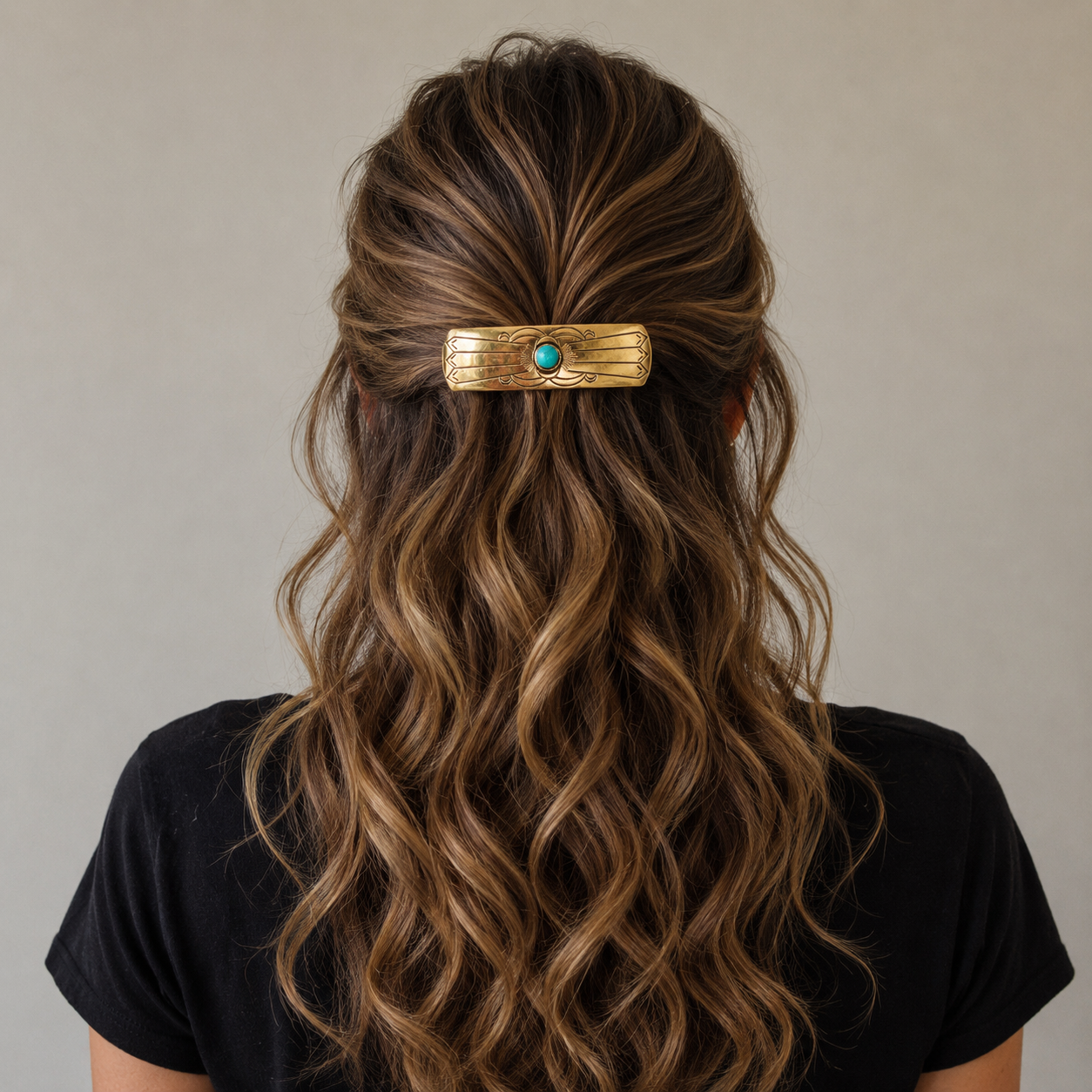 Person with wavy hair wearing a gold hair clip with a turquoise stone on a neutral background | rodeo drive conchos |