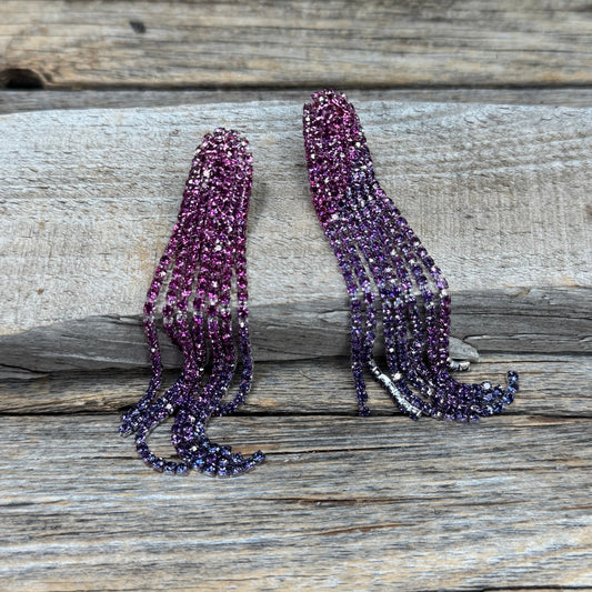 Long, dangling earrings with pink gemstones on a wooden surface