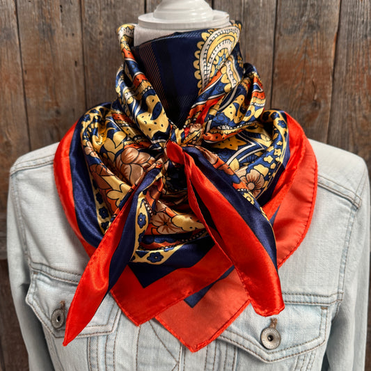 Colorful patterned scarf draped over a light blue denim jacket against a wooden background