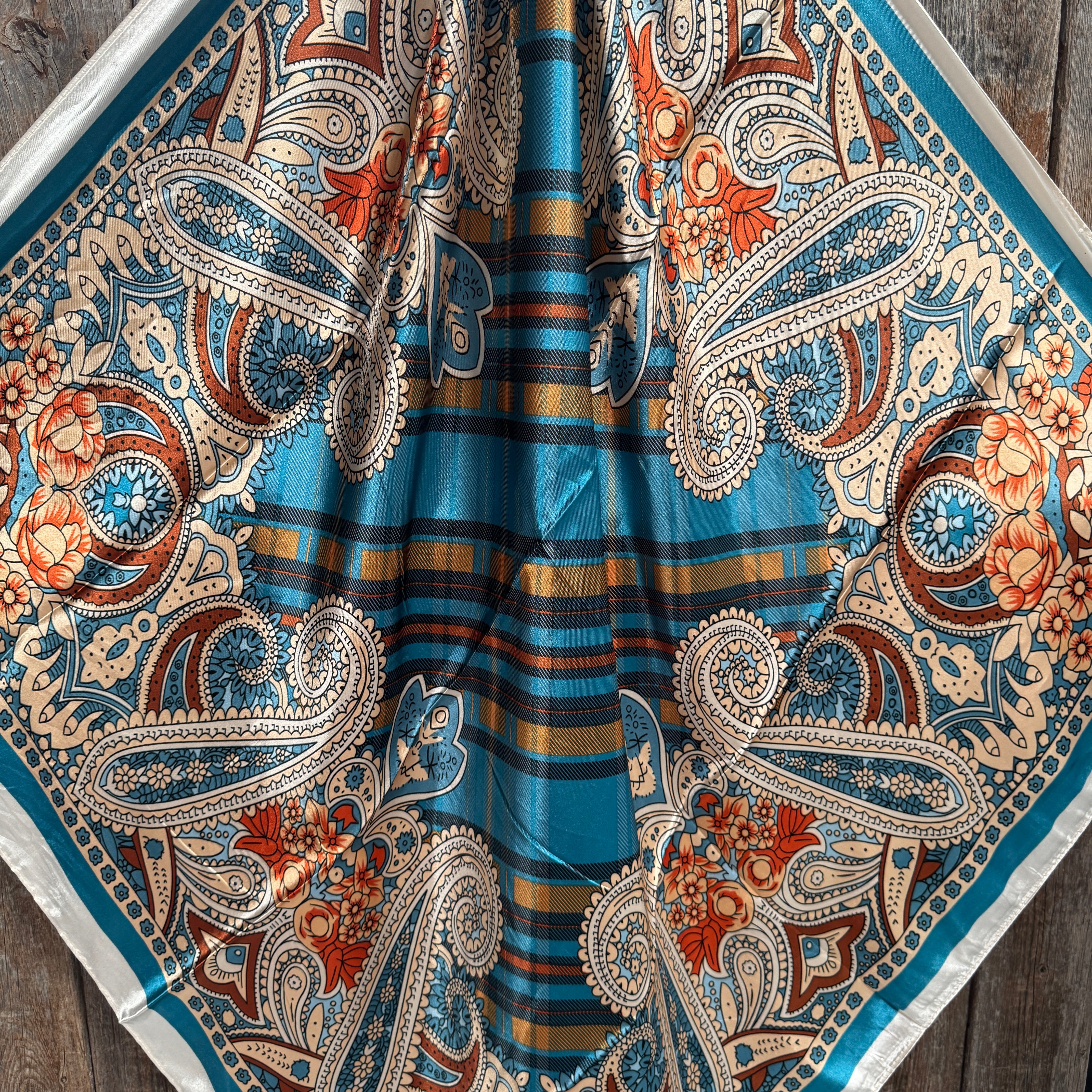 Close-up of a patterned wild rag with paisley and striped design on a wooden surface.