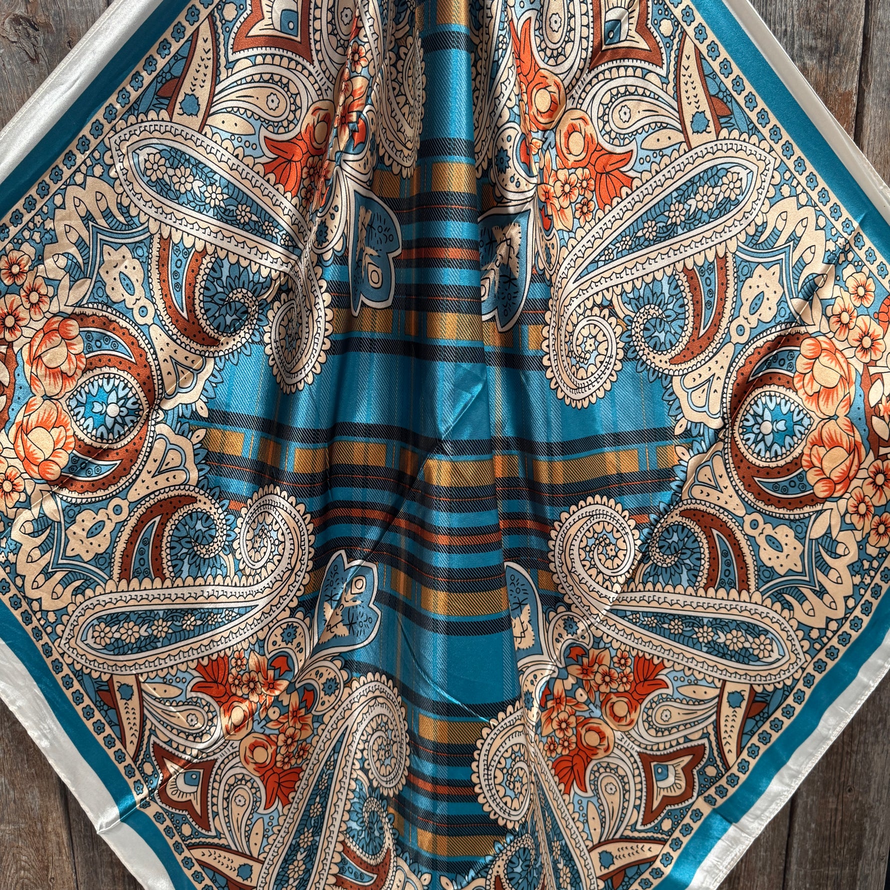 Close-up of a patterned wild rag with paisley and striped design on a wooden surface.