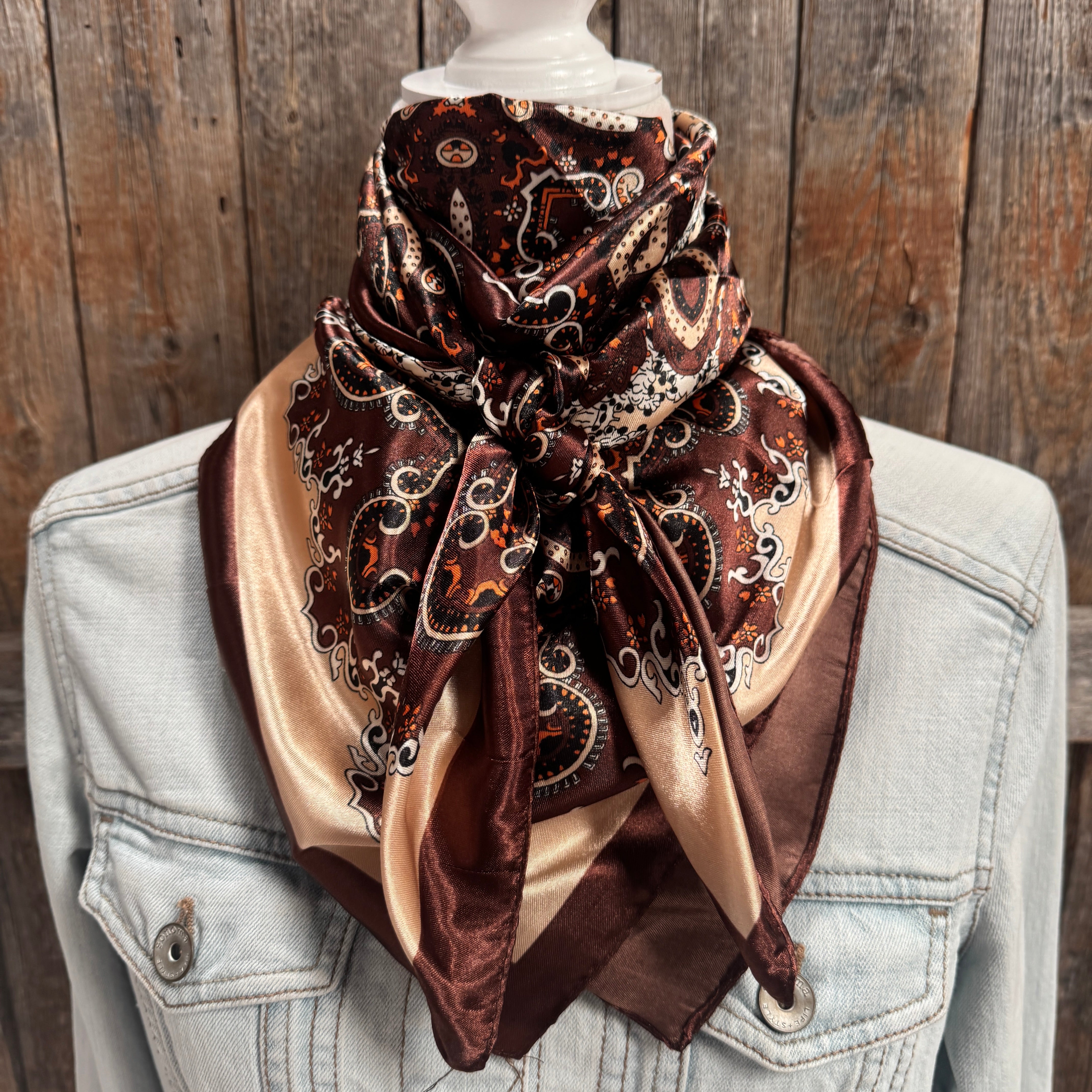 Patterned scarf draped over a light blue denim jacket against a wooden background
