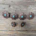 a collection of ornate, copper-colored metal pieces with turquoise stones, arranged on a wooden surface.