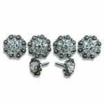 a collection of ornate, sparkling jewelry pieces, including earrings and buttons, arranged in a row.