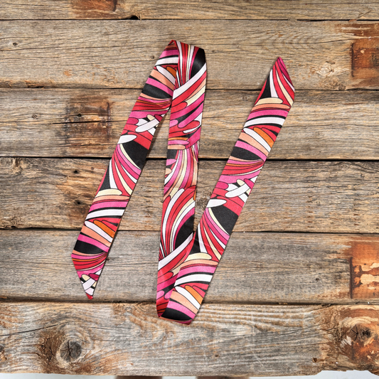 A colorful, patterned scarf is lying on a wooden surface.