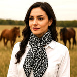 Woman wearing a leopard print scarf with horses in the background